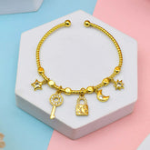Gold bracelet with charms on a hexagonal stone block against a pastel background
