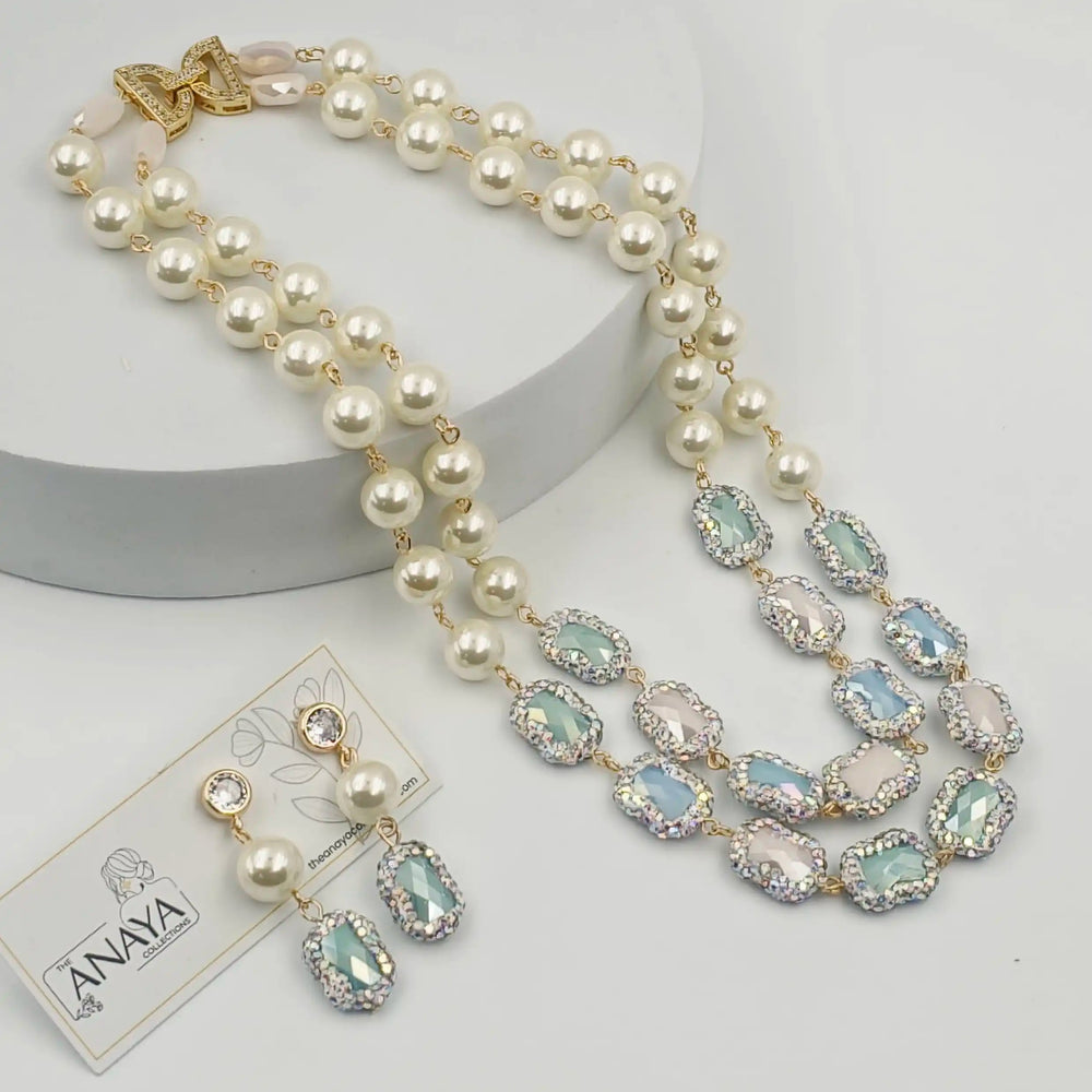 Pearl necklace with gemstone accents and matching earrings on a white background, featuring the brand 'The Anaya Collections'.