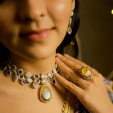 Close-up of a person wearing a decorative necklace and ring with a blurred background