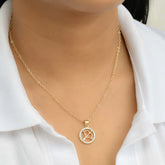 Gold necklace with a circular sagittarius zodiac pendant on a person wearing a white shirt.