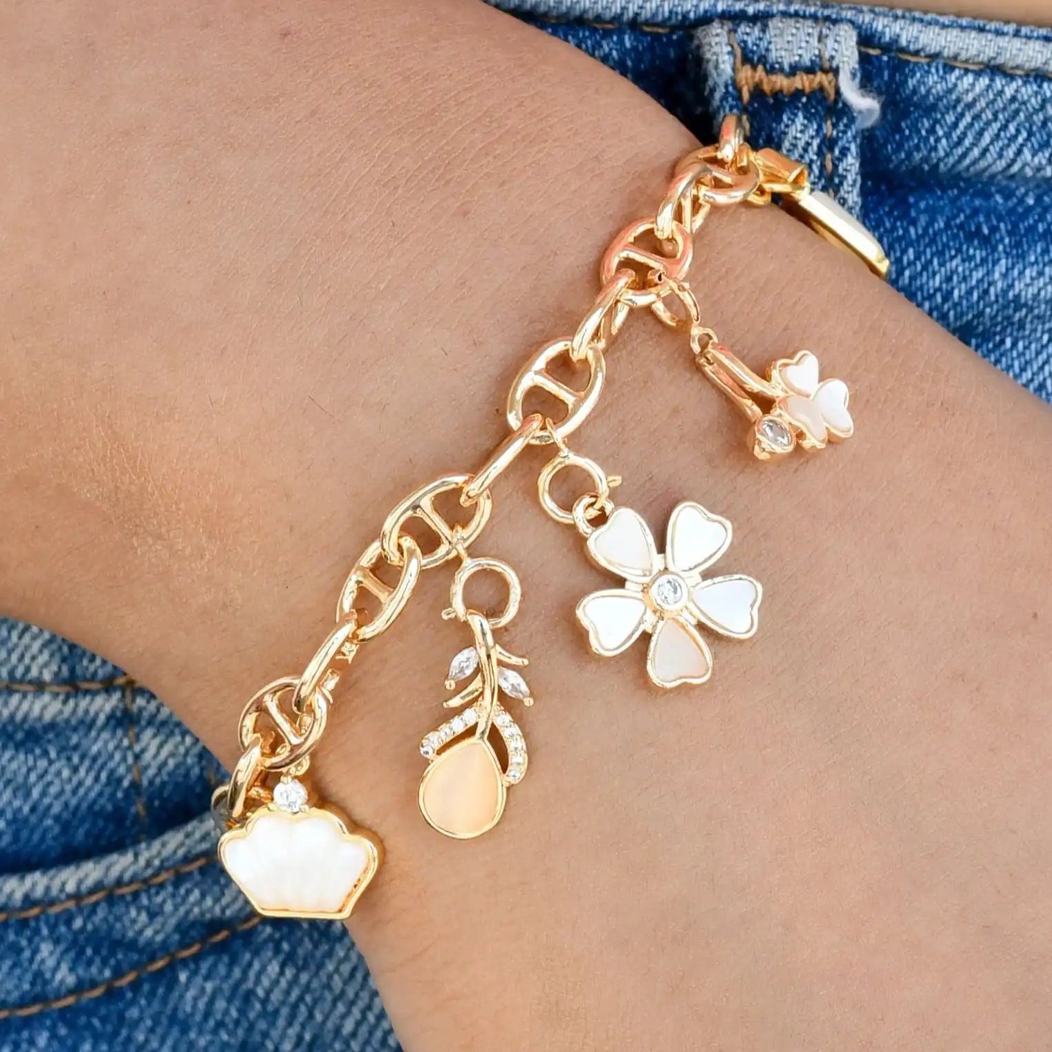 Gold anklet with charms on a person's ankle against a denim background
