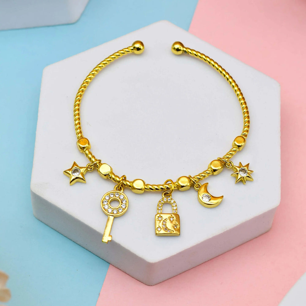 Gold bracelet with charms on a hexagonal stone block against a pastel background