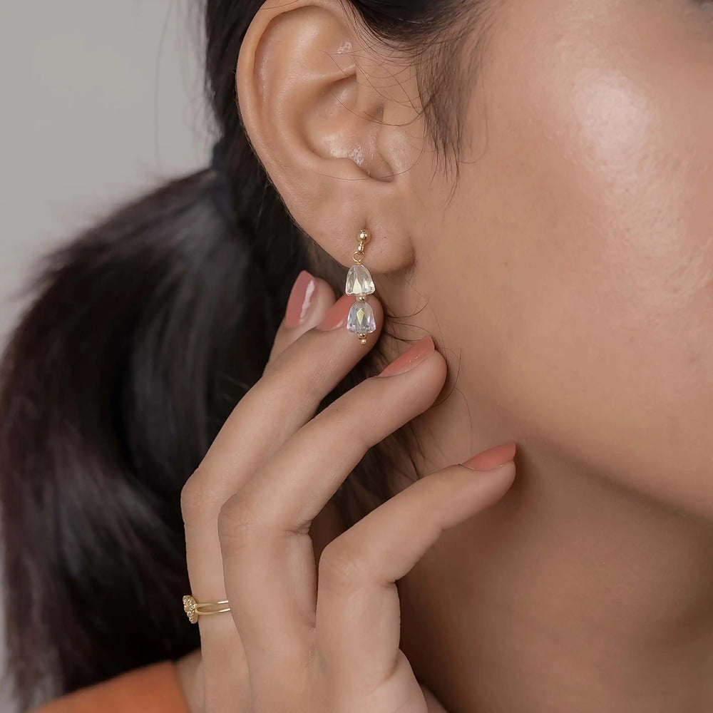 Close-up of a woman wearing a teardrop-shaped earring with a hand adjusting it.