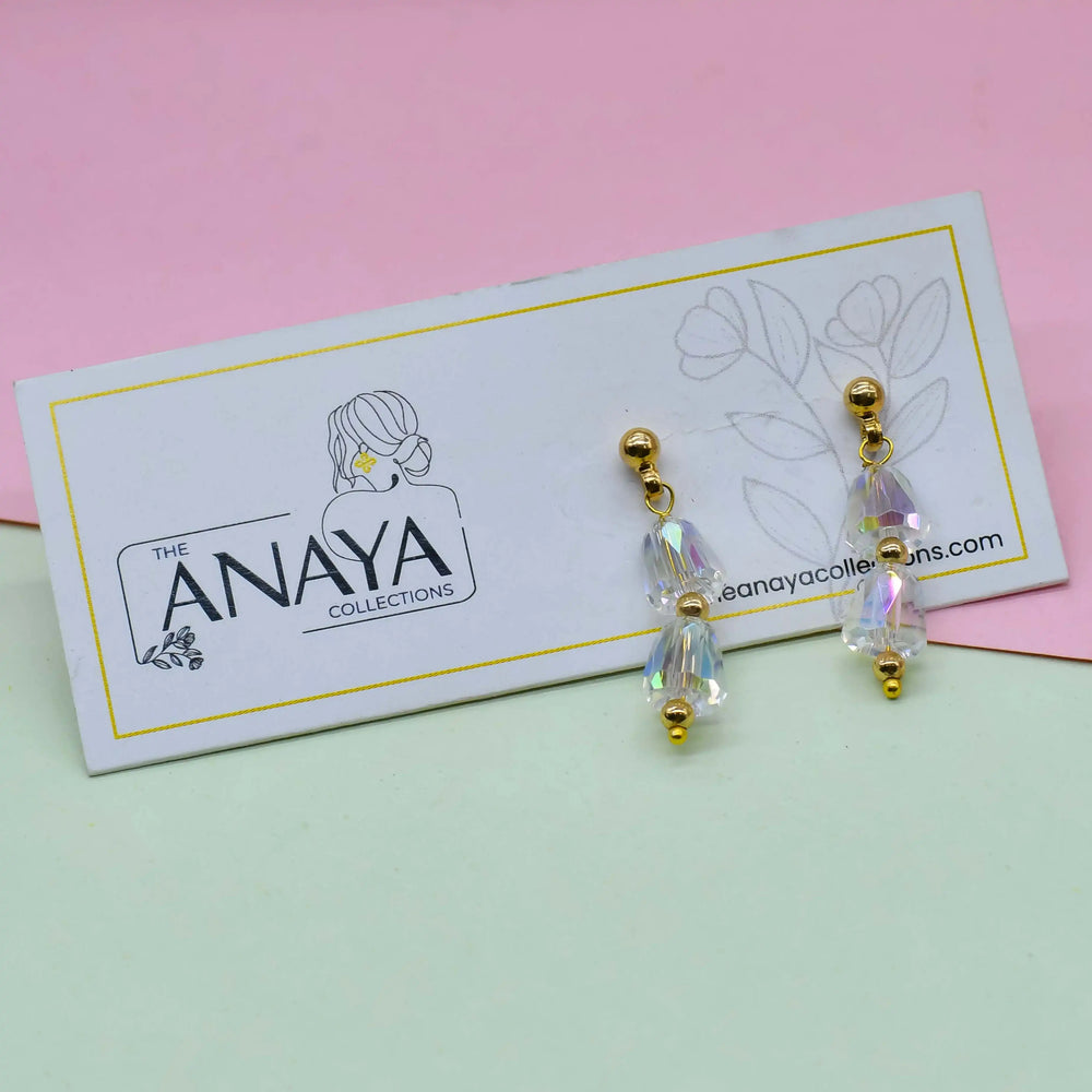 Earrings on a card with 'The Anaya Collections' branding against a pink and green background
