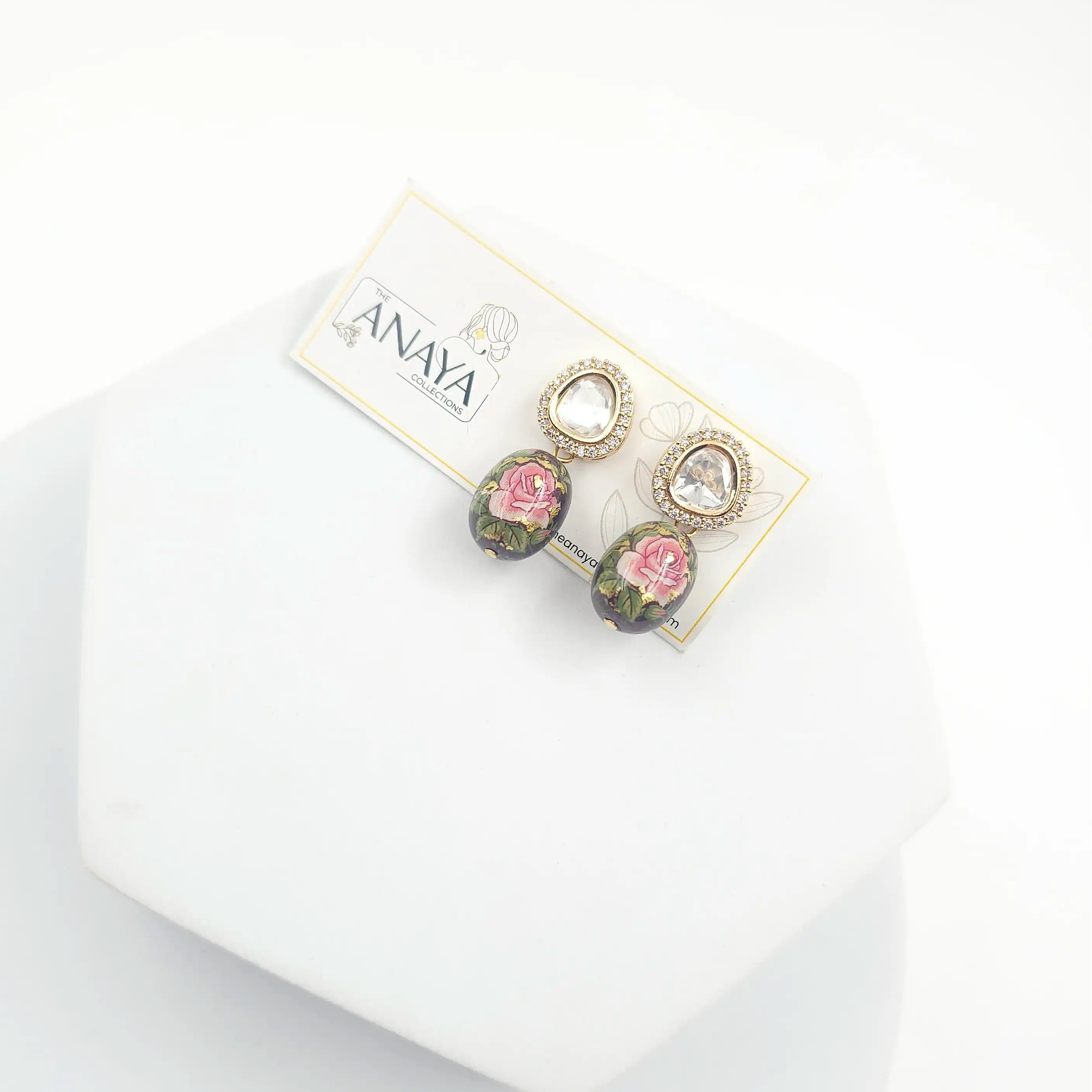 Pair of earrings on a branded card with a white background