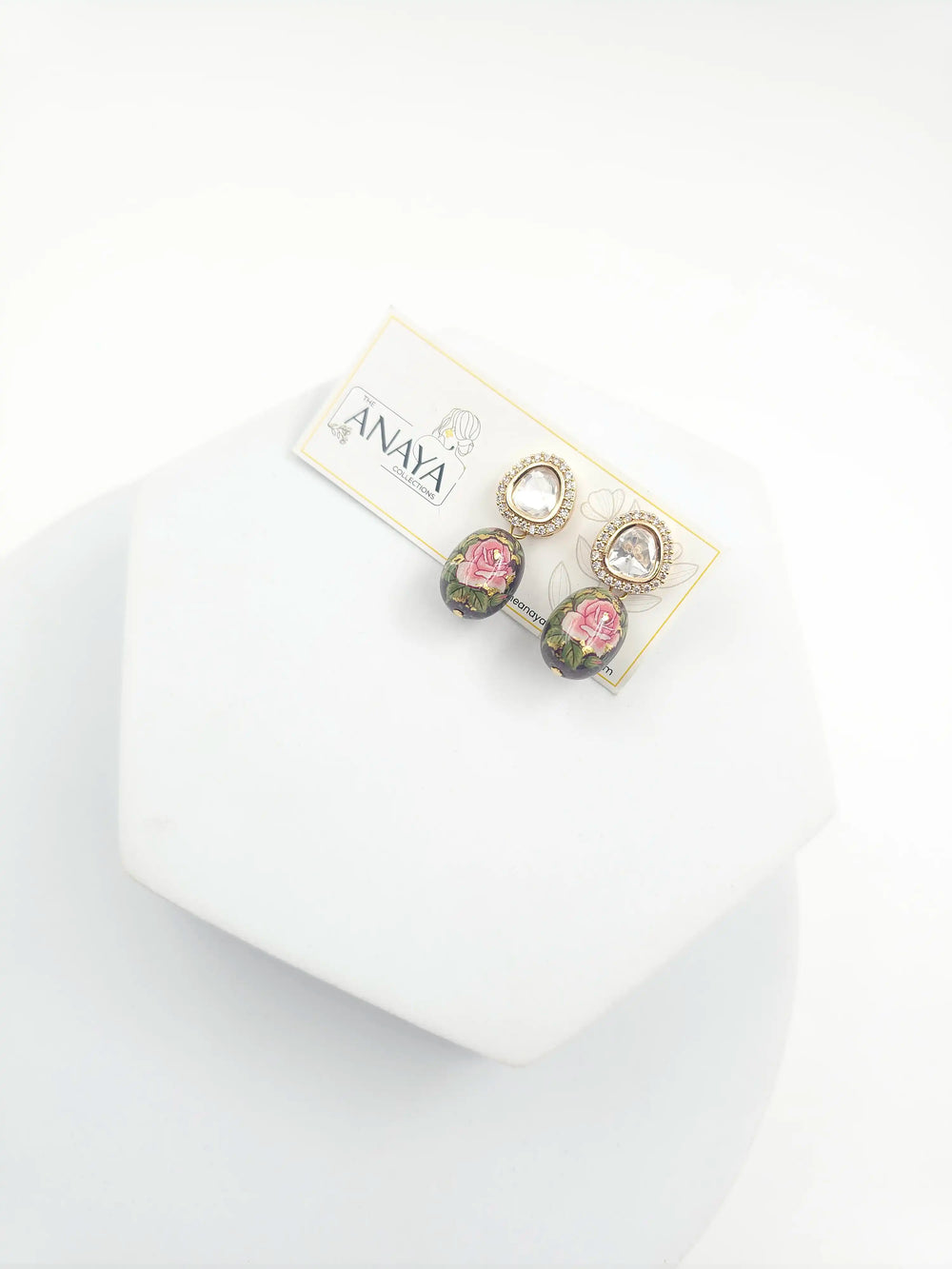 Pair of earrings on a branded card with a white background