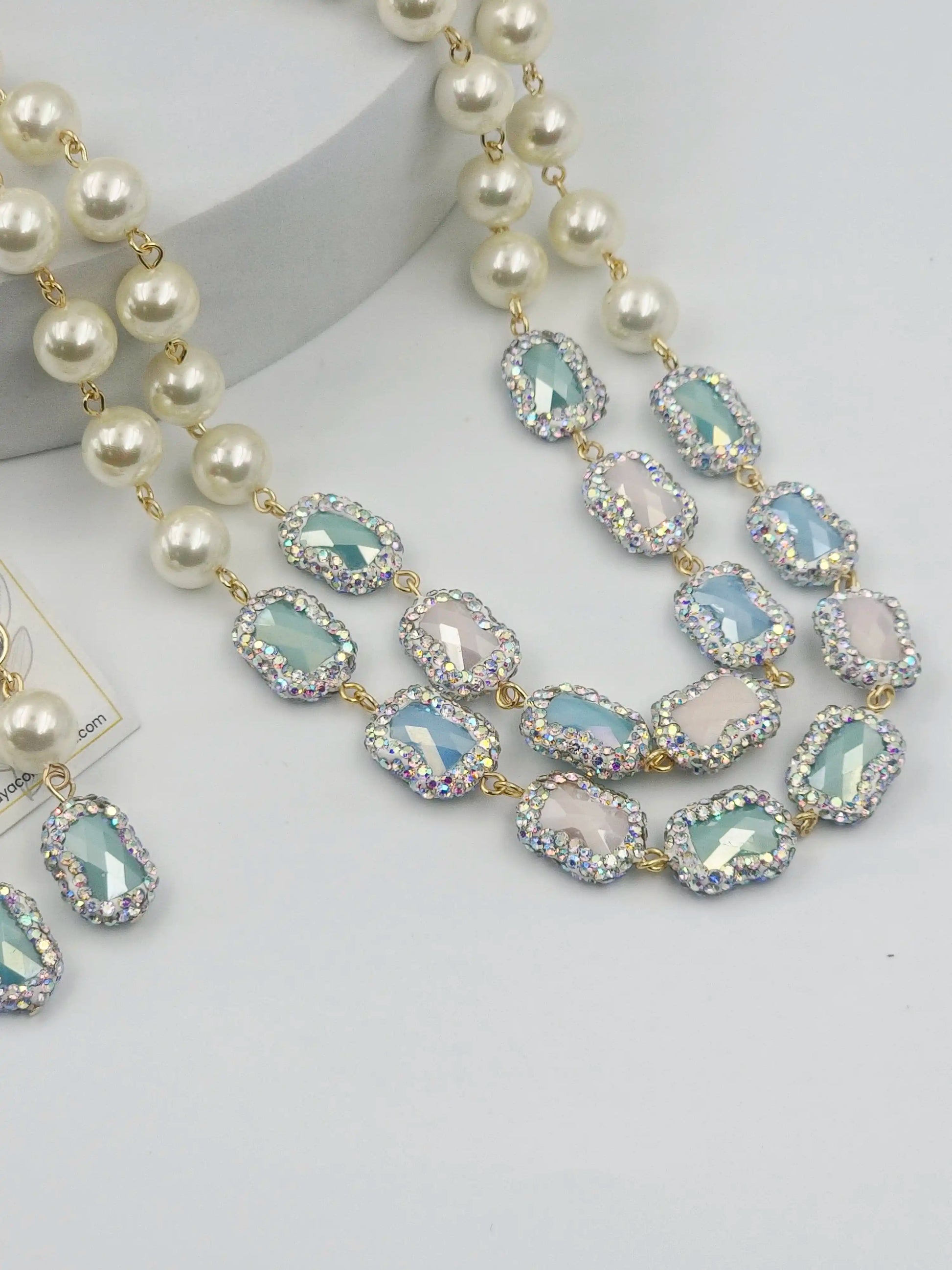 Necklace with pearls and light blue gemstones on a white background