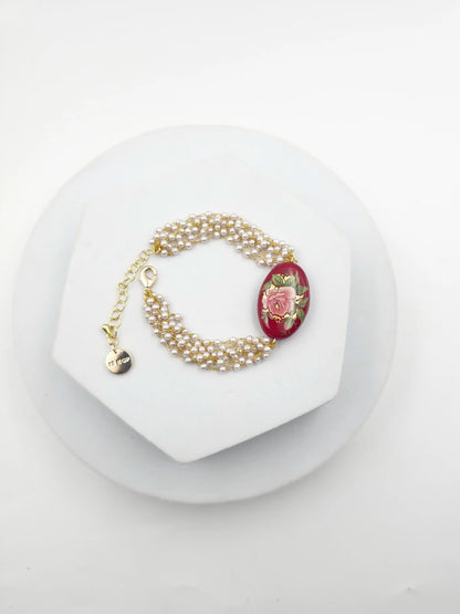 Pearl bracelet with a red flower charm on a white stand