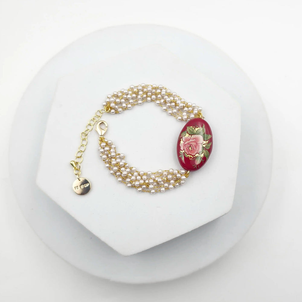 Pearl bracelet with a red flower charm on a white stand