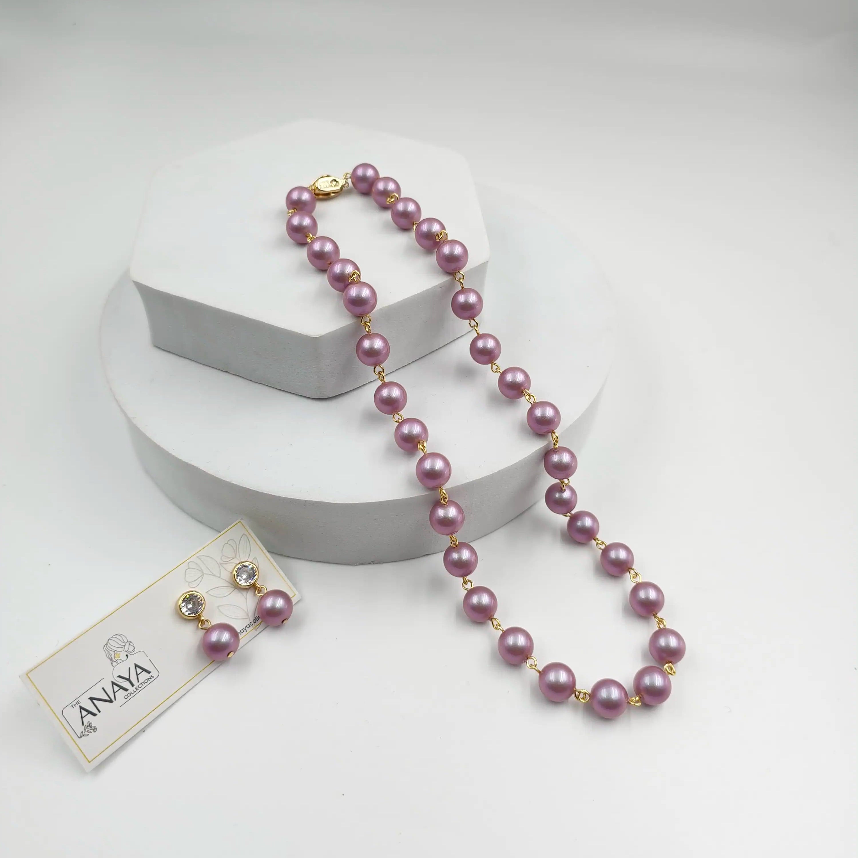 Purple pearl necklace with a tag on a white background